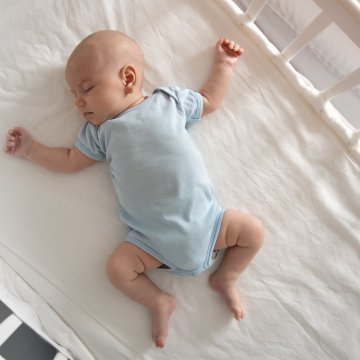 baby in blue clothing in a white crib